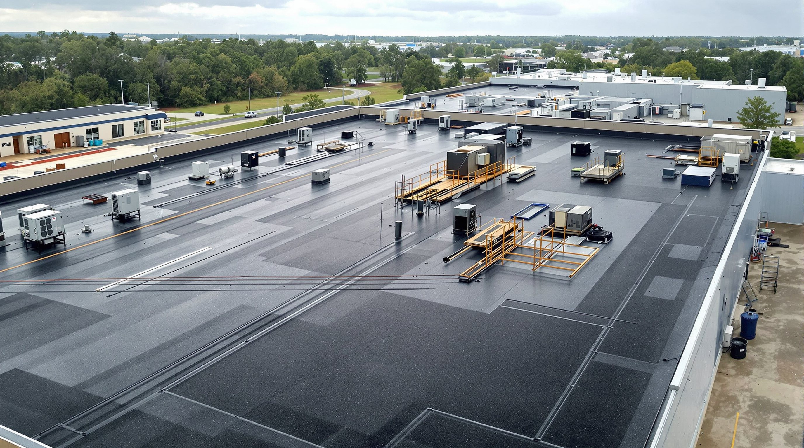 Wide view of a completed EPDM rubber roof installation on a large commercial warehouse building in Mobile County Alabama, showing the 60-mil fully adhered synthetic rubber membrane covering the expansive low-slope roof plane where EPDM delivers the greatest cost advantage over TPO and PVC for budget-conscious commercial roofing projects on the Gulf Coast